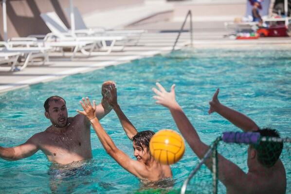 A swimming pool with people playing, lounge chairs, and a poolside area. - Elinotel Sermilia (Polygyros)