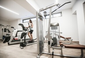 Un gimnasio con máquinas de cardio, equipo de levantamiento de pesas y una banca.