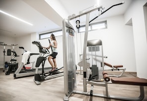 A gym with cardio machines, weightlifting equipment, and a bench.
