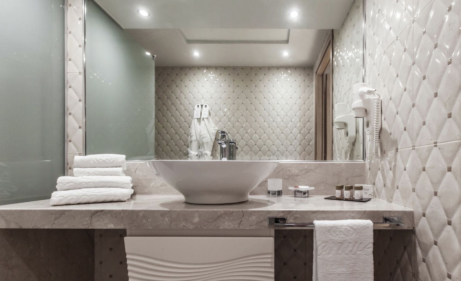 Un baño moderno con un lavamanos independiente grande, un espejo y un perchero para toallas.