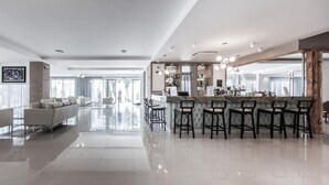 Een moderne hotellobby met een bar, zitplaatsen en uitzicht op het buiten.