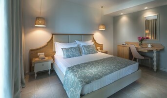 Quarto de hotel com uma cama grande, mesas de cabeceira, uma escrivaninha e uma cadeira.