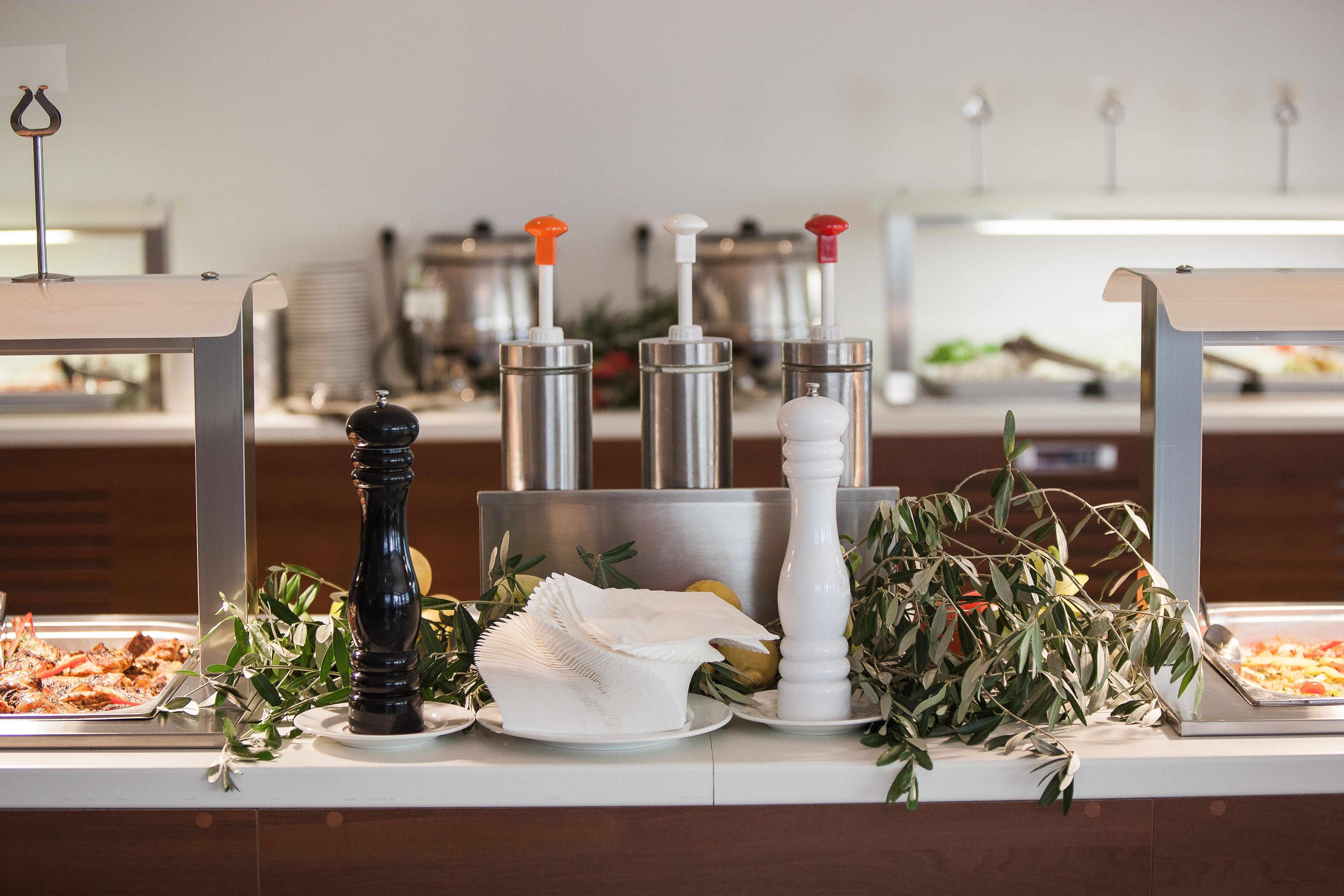A buffet setup with various condiments, a pepper mill, and a salad.