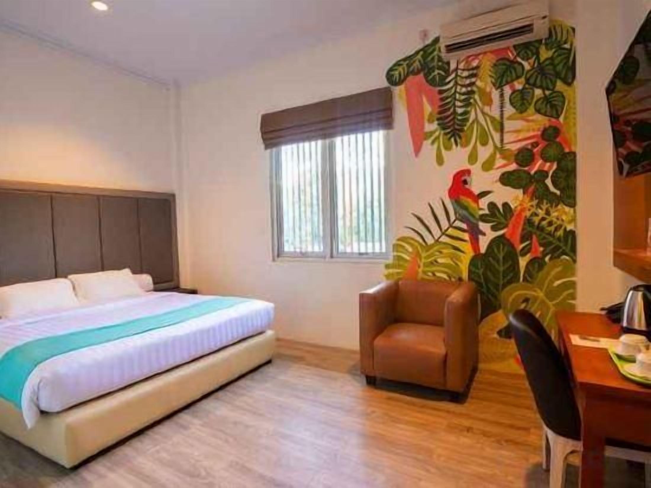 Una habitación de hotel con cama, escritorio, silla y ventana.