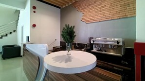 A modern kitchen with a round island, a coffee machine, and a brick accent wall. - Front One Green Boutique Hotel Abepura (Jayapura)