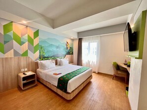 A hotel room with a bed, a desk, a chair, a TV, and a mural on the wall. - Maxone Hotel Jayapura (Jayapura)