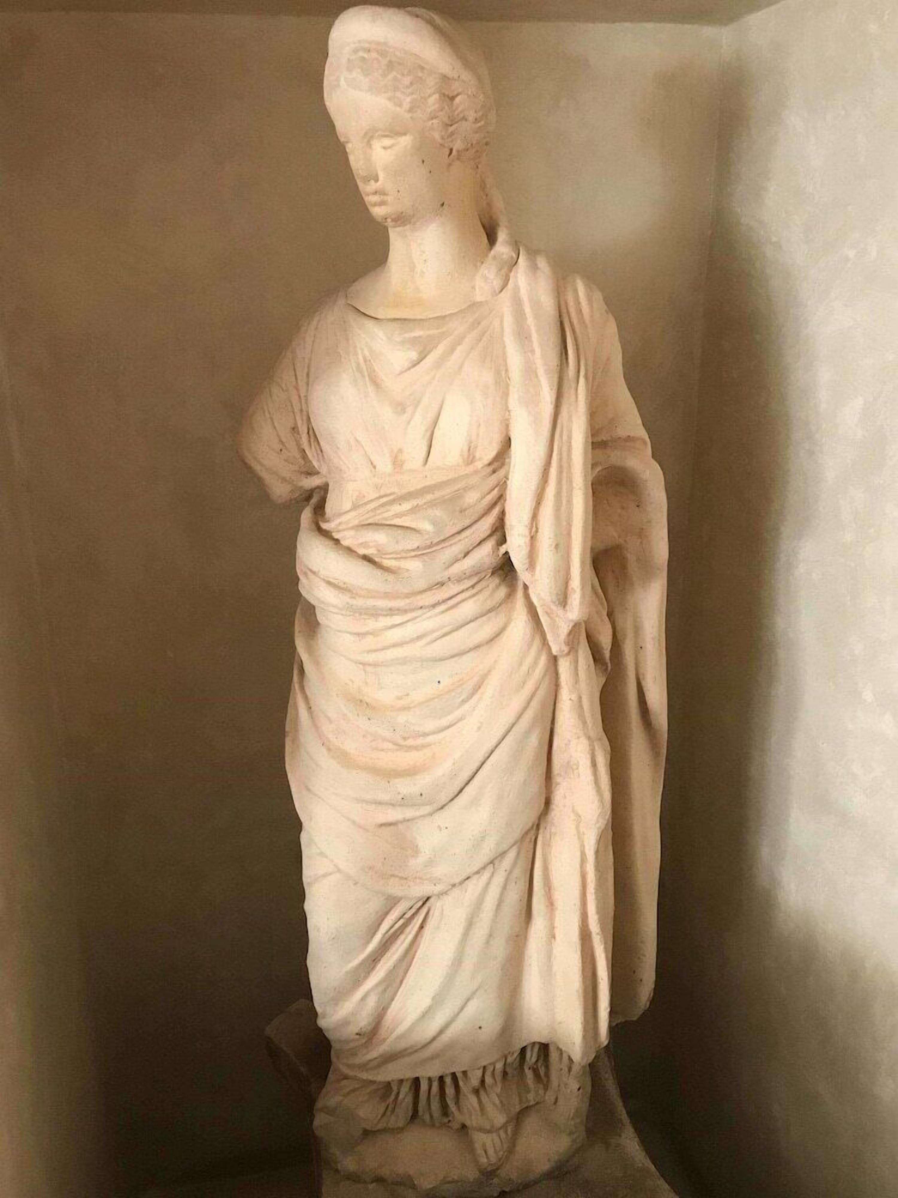 Una estatua de mármol que representa una figura vestida con ropajes, probablemente una representación histórica o clásica.
