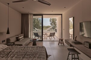 Una habitación de hotel moderna con una cama, un sofá, una mesa de comedor y un balcón con sillas.