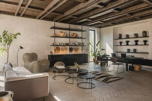 Una sala de estar moderna con techo de madera, un sofá, una mesa de centro y una estantería con objetos decorativos.