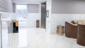 A modern hotel lobby with a marble floor, a reception desk, a sofa, and patterned wall decor. - A Hotels (Brondby)