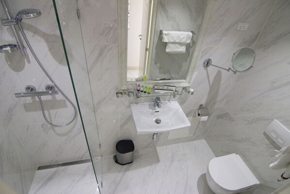 A modern bathroom with a glass-enclosed shower, a white sink, a toilet, and a mirror. - A Hotels (Brondby)