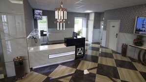 A hotel reception area with a check-in counter, a modern chandelier, and a patterned floor. - A Hotels (Brondby)