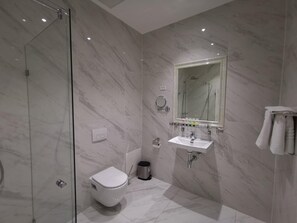 A modern bathroom with a glass shower enclosure, a toilet, a sink, and a mirror. - A Hotels (Brondby)
