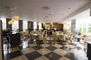 A hotel lobby with checkered flooring, round tables, and chairs, and a reception desk. - A Hotels (Brondby)