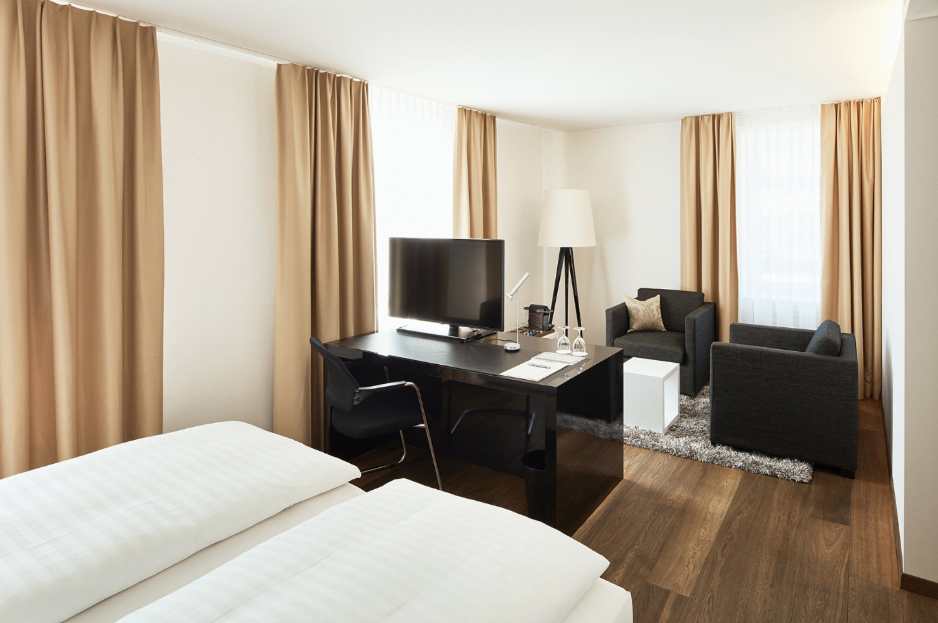 Une chambre d’hôtel avec un lit, un bureau, deux chaises, une télévision et une lampe.