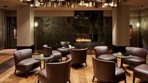 A modern lounge with leather chairs, a fireplace, and contemporary lighting fixtures. - Hotel Uzwil - Ihr Businesshotel (Uzwil)