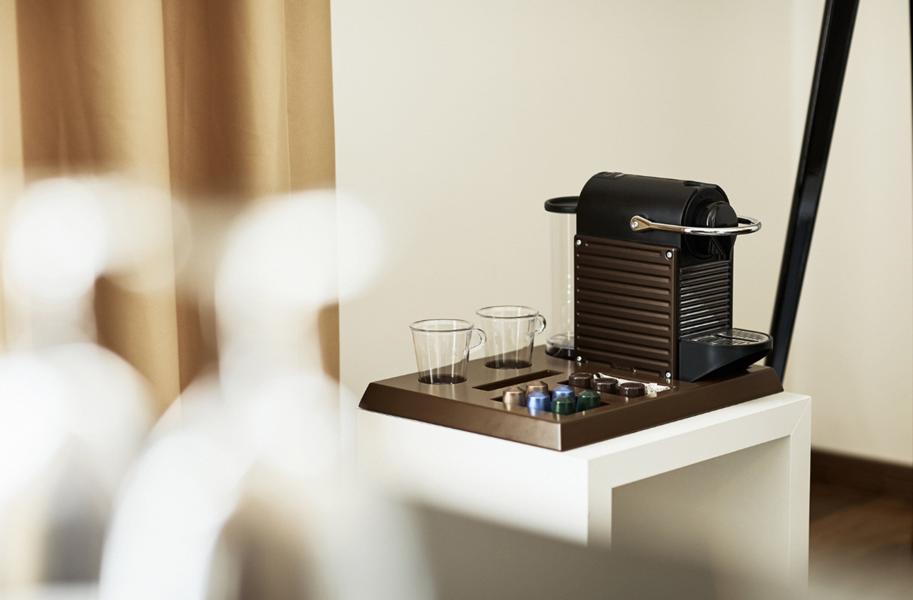 Eine Kaffeemaschine mit Tablett, zwei Gläsern und einer Kaffeekanne auf einem weißen Tisch.