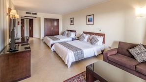 A hotel room with two beds, a desk, a couch, and a TV. - Fort Arabesque The Villas (Makadi Bay)