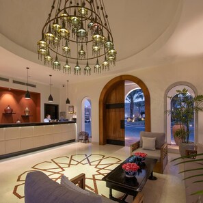 A hotel lobby with a reception desk, a chandelier, seating area, and a view of the outside. - Fort Arabesque The Villas (Makadi Bay)