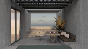 A modern interior with a view of the sea, a stone table, a sofa, and a chair. - Tetra Resort and Spa (Kefalonia)