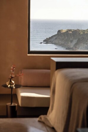 A room with a bed, a nightstand, and a framed picture of a coastal landscape. - Tetra Resort and Spa (Kefalonia)