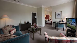 Ein Hotelzimmer mit Wohnbereich, Essbereich, Schlafzimmer und Fernseher.