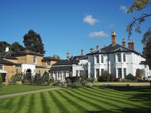 A large, white building with multiple chimneys, surrounded by well-maintained lawns and trees. - Bedford Lodge Hotel and Spa (Newmarket)