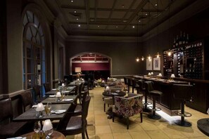 A restaurant with a long counter, multiple tables, and bar seating. - Bedford Lodge Hotel and Spa (Newmarket)