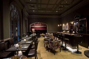 A restaurant with a long counter, multiple tables, and bar seating.