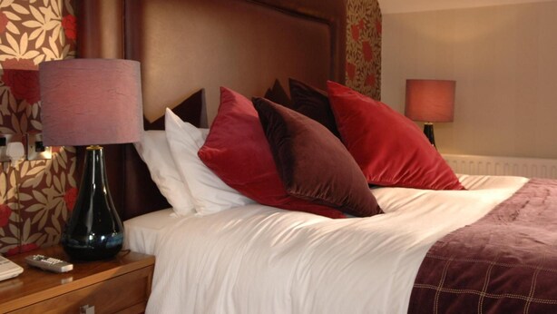 Une chambre d’hôtel avec un grand lit, une table de chevet avec une lampe et un papier peint à motifs floraux.