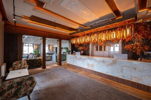 Eine Hotelhalle mit einer Rezeption, einer Sitzecke und Blick ins Innere.