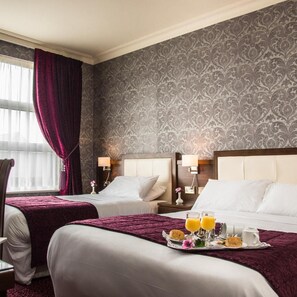 Une chambre d’hôtel avec deux lits, une grande fenêtre avec des rideaux et un plateau contenant des articles pour le petit-déjeuner.