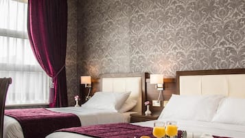 A hotel room with two beds, a large window with curtains, and a tray with breakfast items.