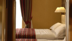 Een hotelkamer met twee bedden, een lamp en een raam met gordijnen.