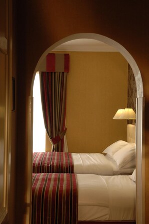 Une chambre d’hôtel avec deux lits, une lampe et une fenêtre avec des rideaux.