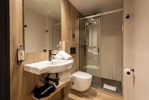 Un bagno moderno con un mobile bagno in legno, un lavabo bianco, un water e una cabina doccia in vetro.