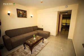 Una sala de estar con un sofá marrón, una mesa de centro de madera y un cuadro en la pared.