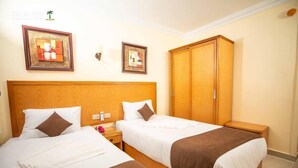 A hotel room with two beds, wooden headboards, and a wardrobe. - Palm Inn Hotel (Hurghada)