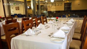 A restaurant with tables set for dining, chairs, and a view of the dining area through a glass wall. - Palm Inn Hotel (Hurghada)