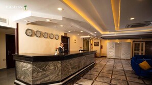A hotel reception area with a marble reception desk, multiple clocks, and a blue sofa. - Palm Inn Hotel (Hurghada)
