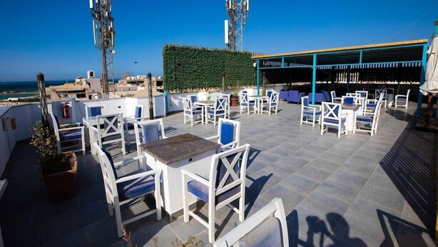 A rooftop terrace with outdoor seating, a view of the sea, and a green hedge. - Palm Inn Hotel (Hurghada)