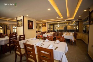 A hotel dining area with multiple tables and chairs, featuring a modern design with recessed lighting and framed artwork on the walls. - Palm Inn Hotel (Hurghada)