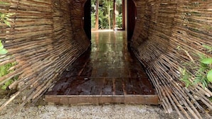 Un arco de bambú que da paso a una puerta de madera.