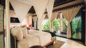 Un dormitorio con cama con dosel, un sofá y vistas a la vegetación.