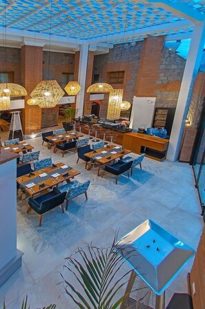 A spacious indoor area with multiple dining tables and chairs, a bar area, and a decorative ceiling. - Hotel Otavalo (Otavalo)