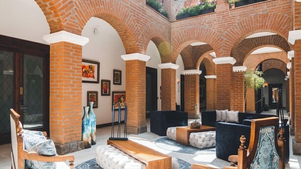 A spacious lobby with brick arches, comfortable seating, and artwork on the walls. - Hotel Otavalo (Otavalo)