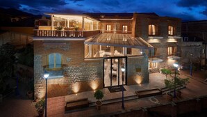 A multi-story hotel with a stone facade, large windows, and a balcony. - Hotel Otavalo (Otavalo)