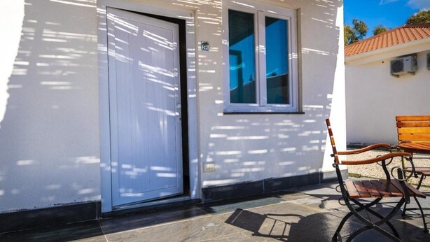 A white building with a closed door, a window, and a bench outside. - Futura Club Acqua Di Venere (Capaccio-Paestum)