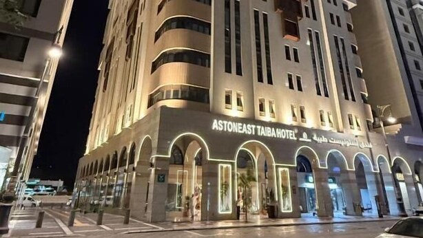 A multi-story hotel with a prominent entrance and illuminated signage. - Astoneast Taiba Hotel Ex Artal Al Alami  (Madinah)