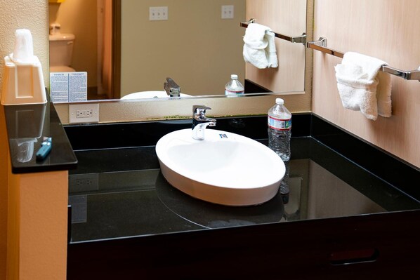 A hotel bathroom with a round sink, a mirror, and a towel rack. - Hermiston Inn & Suites (Hermiston)